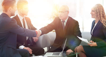 Partners concluding deal and shaking hands in the presence of team membersの写真素材
