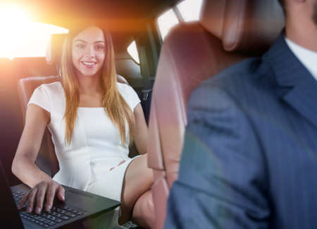 Executive businesswoman in car work on her laptop.