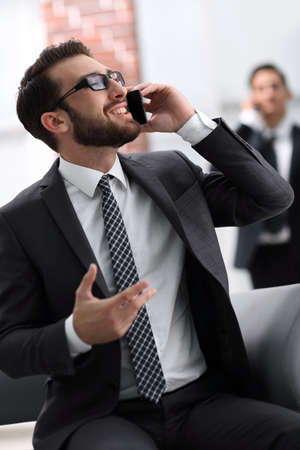 Handsome businessman speaking on mobile phone in officeの写真素材