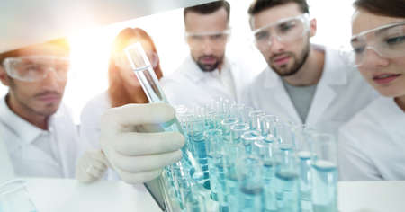 background image is a group of microbiologists studying the liqu