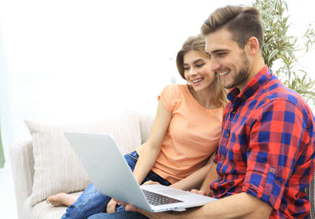 smiling young couple with laptop sitting on the couch