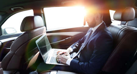 businessman using a laptop in the backseat of a carの写真素材