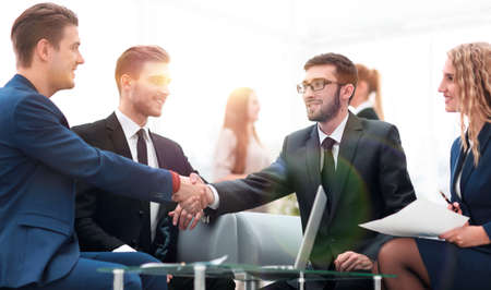 Partners concluding deal and shaking hands in the presence of team membersの写真素材