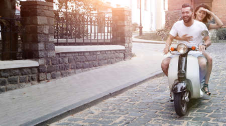Young couple riding motor scooter in cityの写真素材