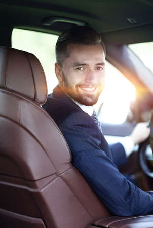 Handsome young man sitting in the front seat of a car looking atの写真素材