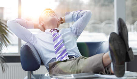 Young businessman leaning back in his chairの写真素材