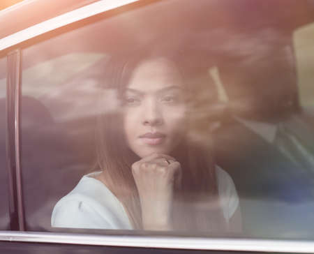 thoughtful business woman sitting in car backseatの写真素材