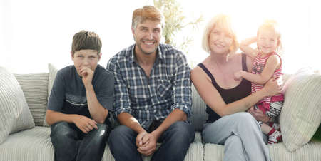 Young couple with their cute kids having rest at homeの写真素材