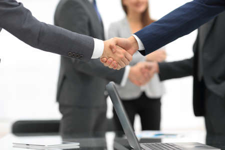 Men shaking hands with smile at office with their coworkers.