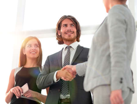 Business people shaking hands against room with large window