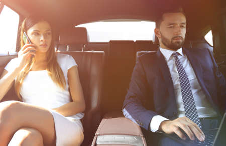 businesswoman talking on the phone in the back seat of the carの写真素材