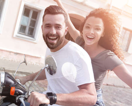 Cheerful young couple riding a scooter and having funの写真素材
