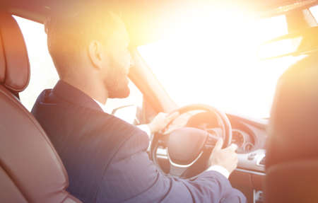 businessman sits at the wheel in his car and looks at the roadの写真素材