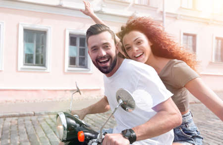 Cheerful young couple riding a scooter and having funの写真素材