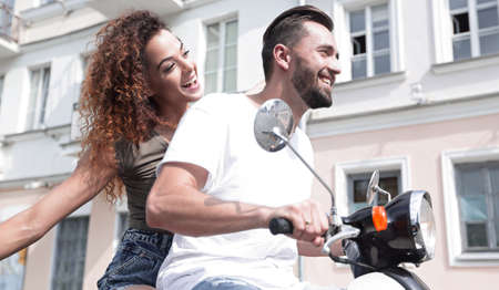 Happy young couple having fun on a scooterの写真素材