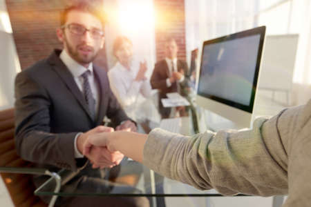 businessman shaking hands with a business partner sitting near your desktopの写真素材