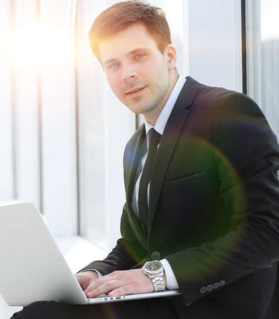 young professional with laptop on background of office window