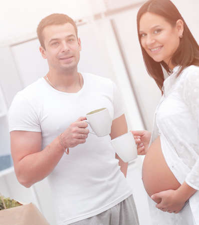 husband and his pregnant wife drinking cocoa ,standing in the kitchen.の写真素材