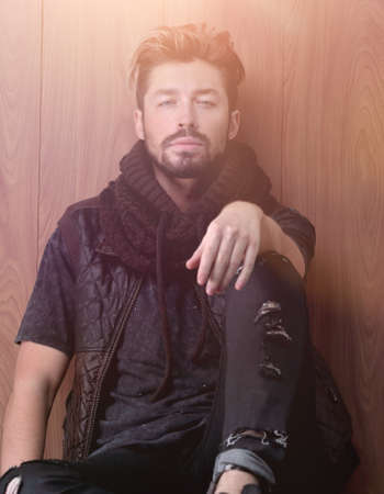 Handsome mature man sitting by the brick wall. Mens fashion.