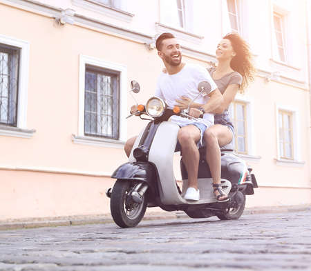 Full length side view of happy couple riding on retro motorbikeの写真素材