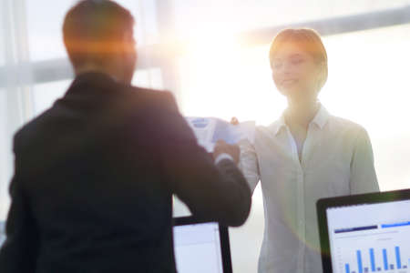 senior Manager, handing the employee a document with financial data.