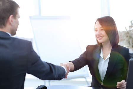 business woman shaking hands with a business partner over a Desk