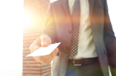 Businessman giving a card. Close-up photo in loft officeの写真素材