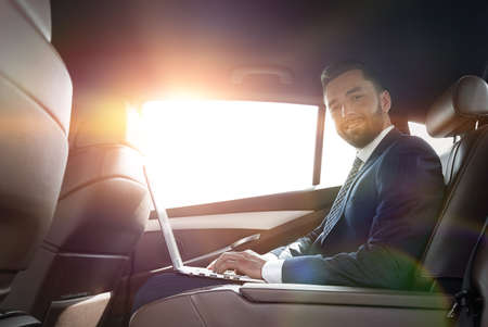 smiling businessman sitting in the back seat of a prestigious caの写真素材