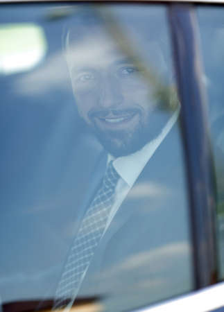 smiling businessman in the back seat of a car.