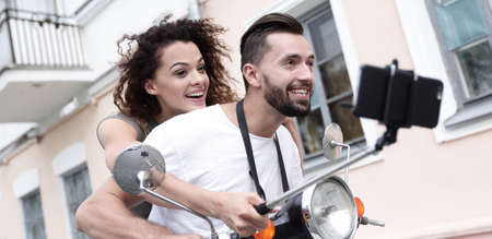 Happy couple on scooter making selfie on smartphone outdoorの写真素材