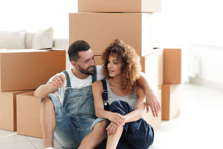smiling couple on the background of large cardboard boxes.