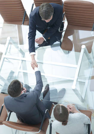 Handshake across the table. Meeting around a boardroom table.