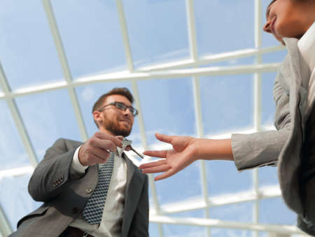 Cropped image of estate agent giving house keys to man in officeの写真素材