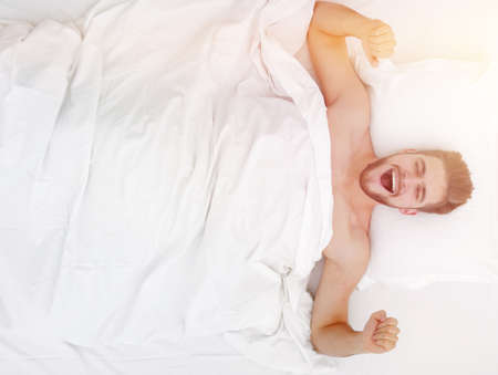 top view. happy man waking up in a comfortable bedの写真素材