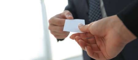Close-up of two businesspeople exchanging visiting cardの写真素材