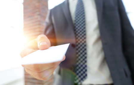 Businessman giving a card. Close-up photo in loft officeの写真素材