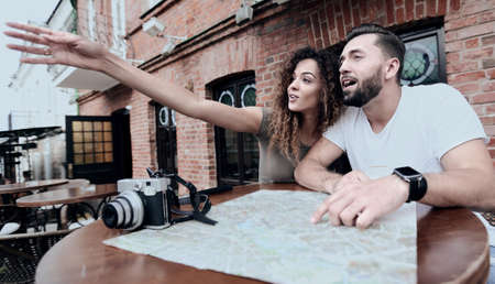 Young  tourists drinking coffee at cafe and reading city mapの写真素材