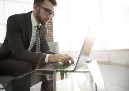 Portrait of young man sitting at his desk in the officeの写真素材
