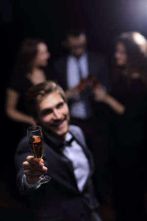 stylish young man raising his glass in a toastの写真素材