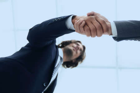 bottom view of two men shaking hands while standingの写真素材