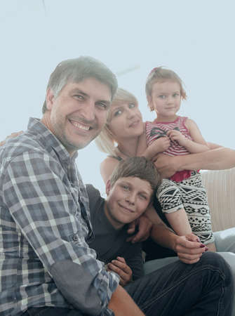 family with two children sitting together and looking at camera