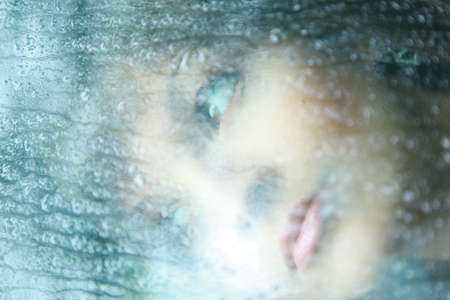 Attractive woman looking out of the window on rainy day