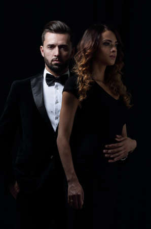 elegant man and woman posing next to each other on studio.の写真素材