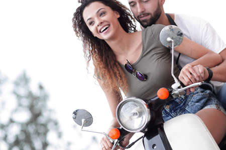 Attractive couple riding a scooter on a sunny day in the cityの写真素材