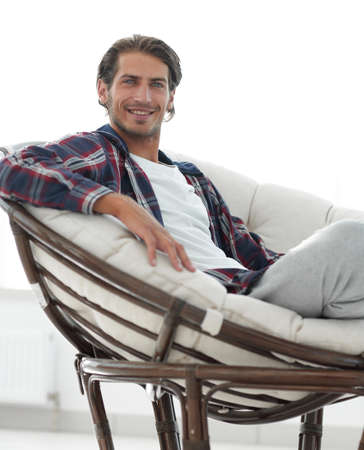 close-up of a smiling guy stroking his dog while sitting in a large armchair.の写真素材