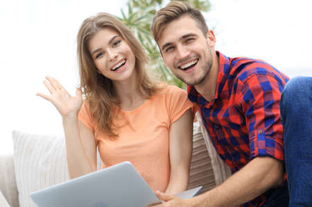 happy couple laughing ,sitting on the couch in front of the open laptop