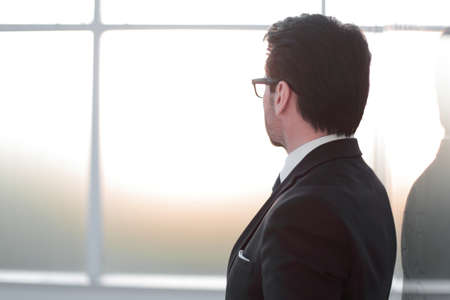 side view. businessman standing near the office window.