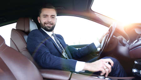 View from the side confident businessman sits at the wheel of a car