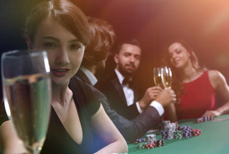 portrait of smiling woman with drink playing pokerの写真素材