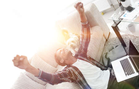 happy guy with his dog sitting in a spacious living roomの写真素材